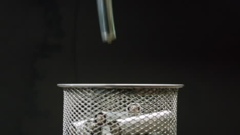 Silver batteries AA and AAA falling into wastebasket close-up. Double-A battery is a standard size single cell cylindrical dry battery. Batteries are common in portable electronic devices. Environmental impacts of lithium-ion batteries concept. An AA battery is composed of a single electrochemical c