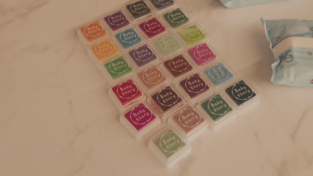 Close up of colorful ink pads labeled Baby Story arranged on a light marble surface
