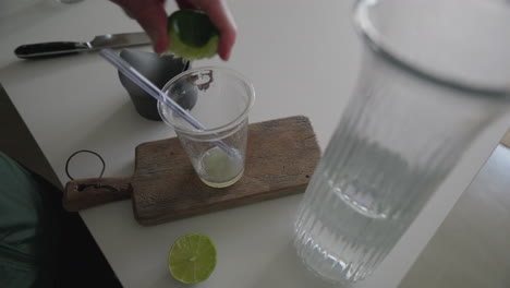 hand squeezing lime into water on rustic kitchen board