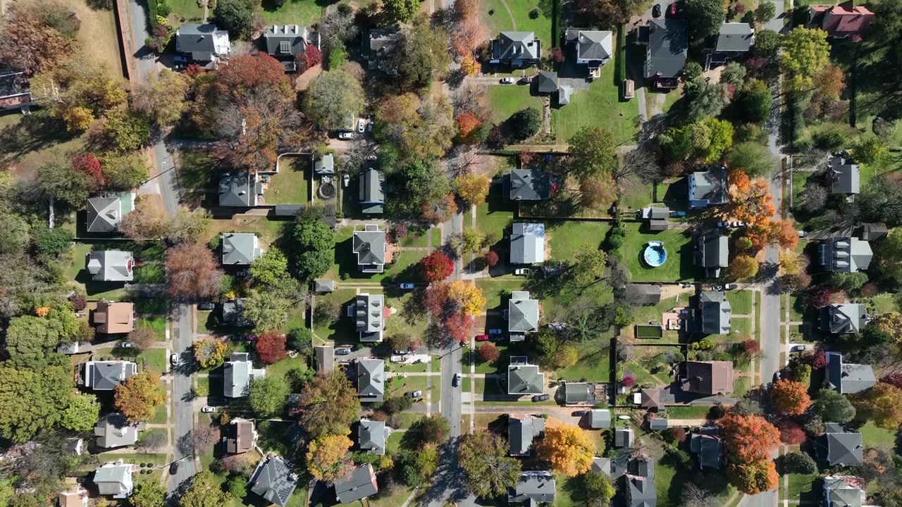 Huse og boliger i et amerikansk kvarter med farverige træer i efterårssæsonen. Top-down luftfoto. Kørende biler på hovedgaden i en forstad til en by i USA. Maine, Amerika