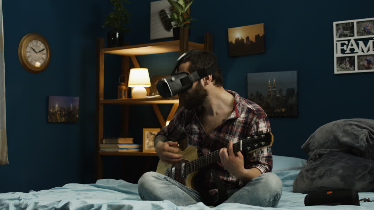 Man Playing Guitar While Wearing VR Headset in Bedroom