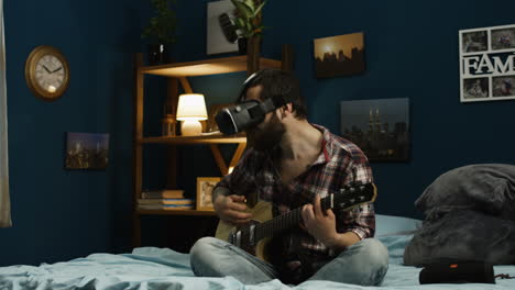 man playing guitar while wearing vr headset in bedroom