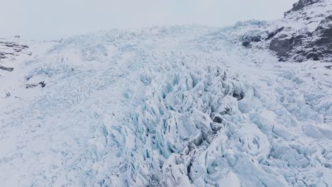 aerial panoramic view over ice formations in falljokull glacier covered in snow, iceland, at sunset