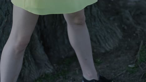 woman in yellow dress dancing by tree in summer park