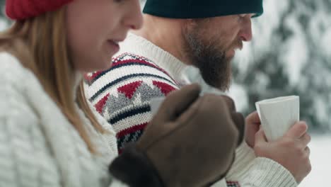 Close-up-of-couple-drinking-hot-tea-and-talking-together-in-winter-time