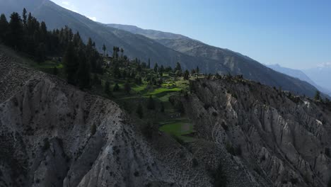 Vista-Aérea-Del-Pueblo-De-Acantilados-Y-Campos-Verdes-En-El-Norte-De-Pakistán