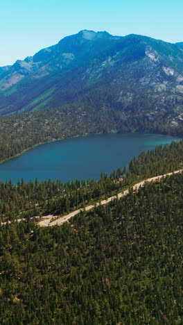 marvelous mountainous landscape with pine trees growing around. little blue lake hiding in the mountains. top view. vertical video