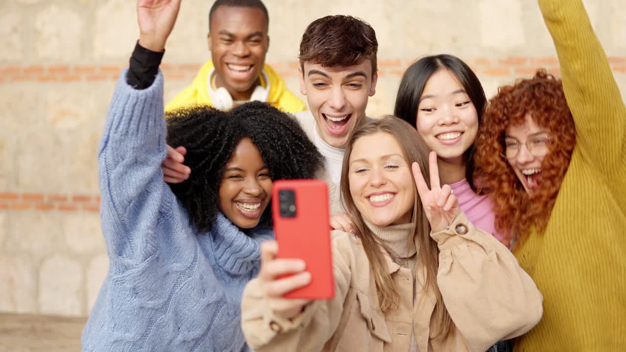 Giovani amici multietnici festeggiano mentre scattano un selfie all'aperto