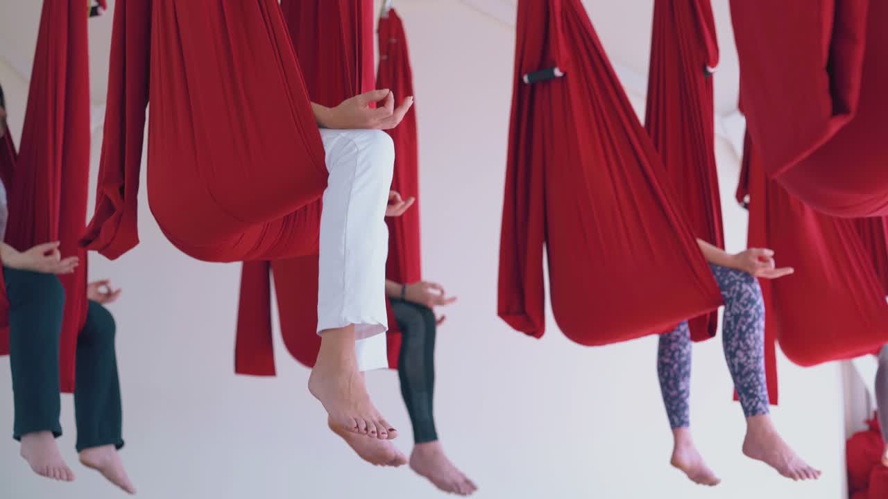 las damas practican el ejercicio de yoga de mosca en la asana de mariposa