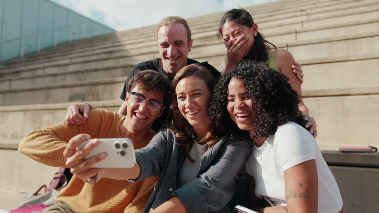 Group of smiling students outdoors using cell phone and taking selfie