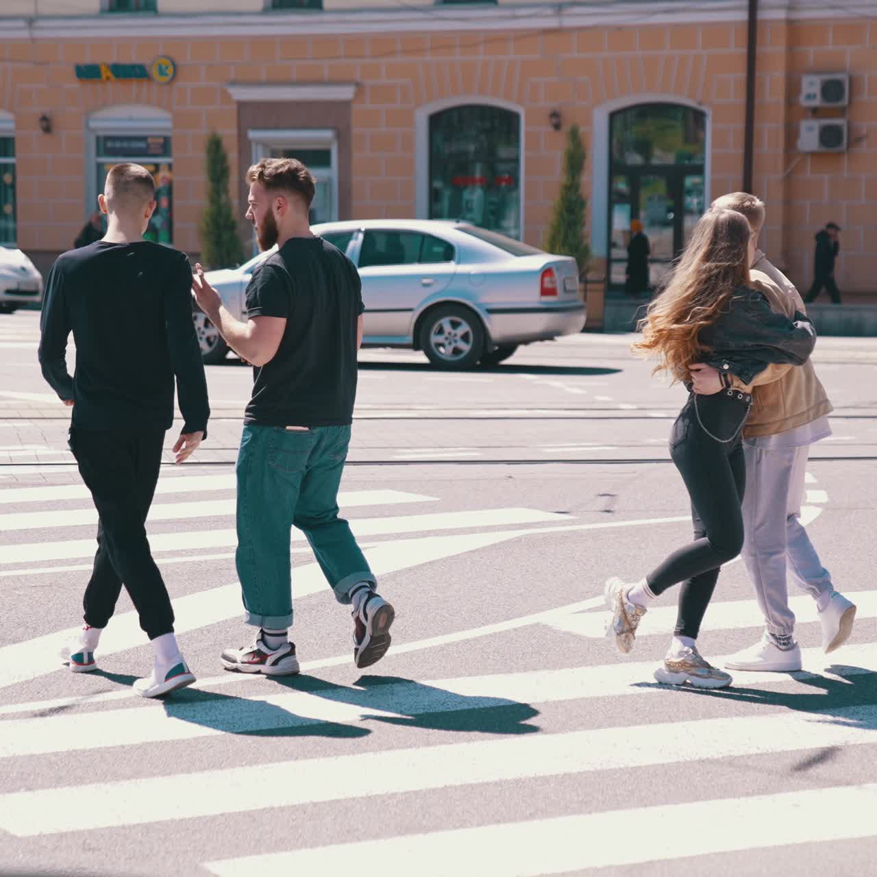 Happy friends walking through the road. Good looking guys spending time with friends in city in a sunny day. Young people enjoying the time together
