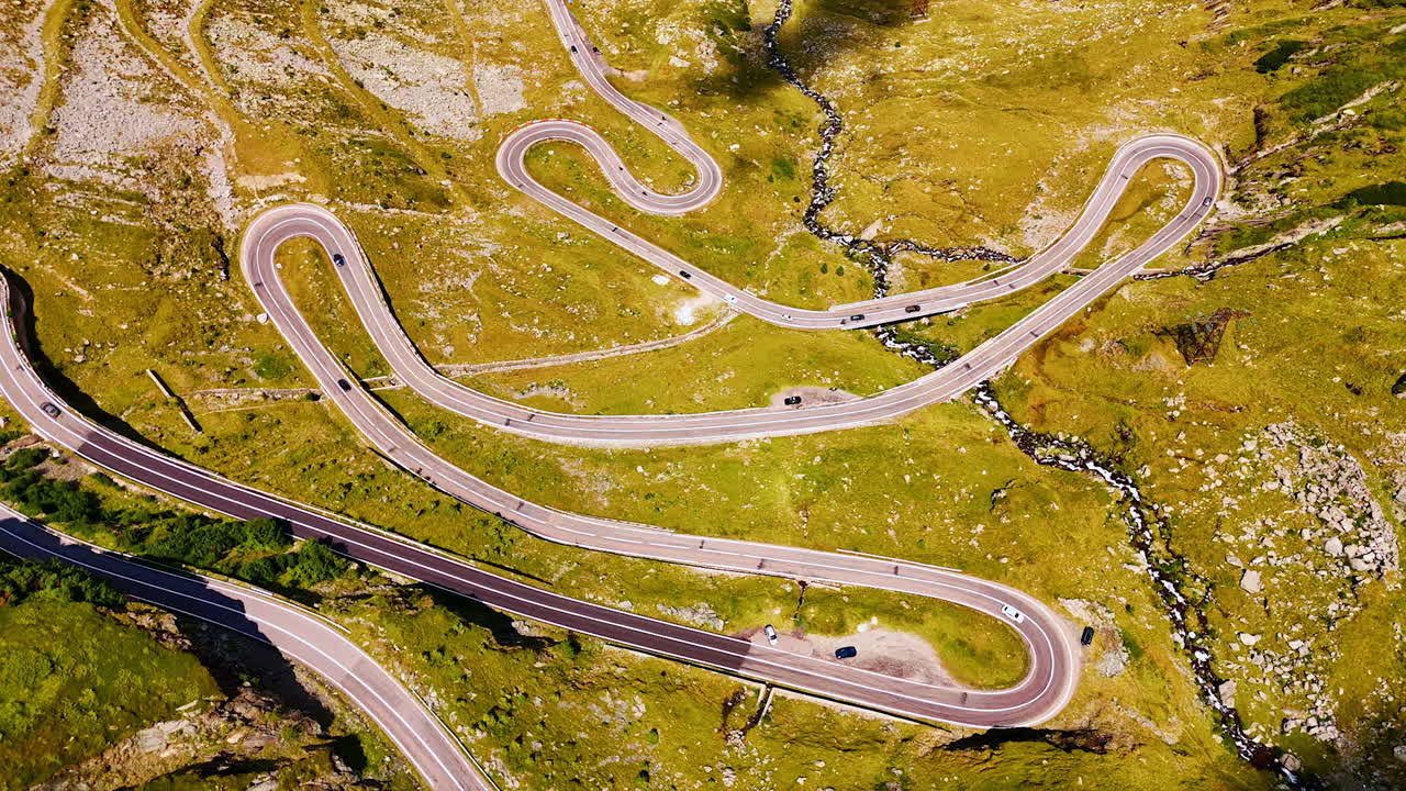 Stunning wavy highway on the mountain slopes. Sunny scenery of Transfagarash highway in Romania. Aerial view
