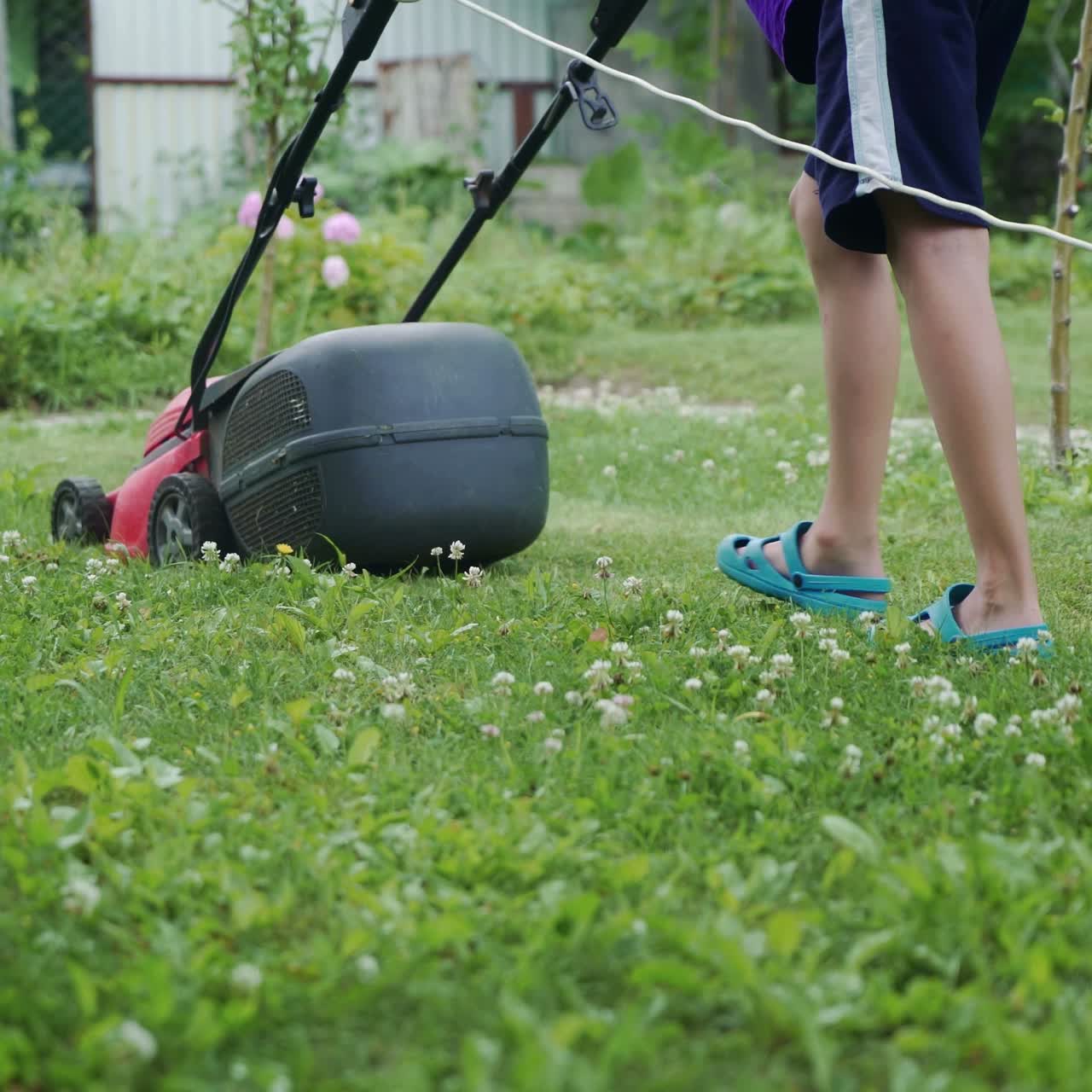 Little boy running with a lawn mower in the garden