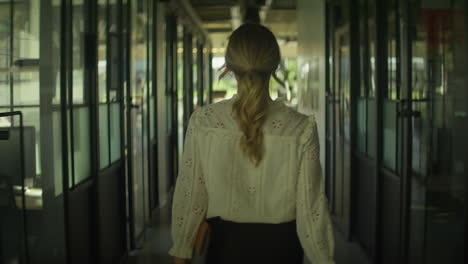 a white woman walks quickly down an office hallway