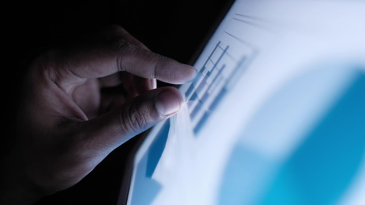 persona que utiliza una tableta para ver gráficos y gráficos por la noche