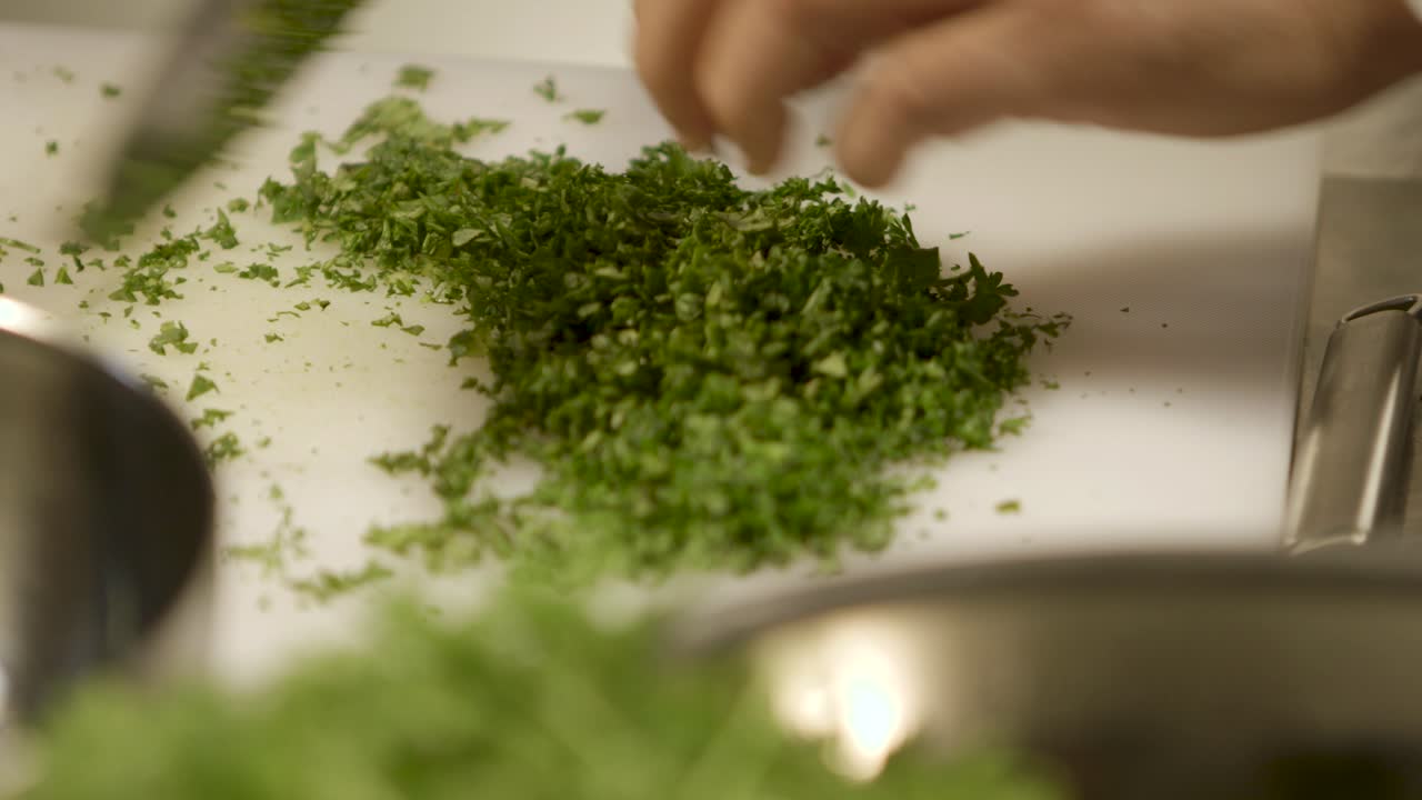 Close-up of a person chopping fresh herbs on a cutting board