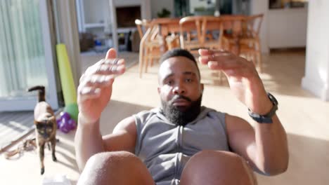 hombre afroamericano enfocado en entrenamiento físico haciendo abdominales en casa, cámara lenta