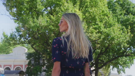 Ukrainian-Beautiful-Blond-Hair-Woman-Model-Strolling-in-Park-Looks-Back,-handheld-slow-motion-shot