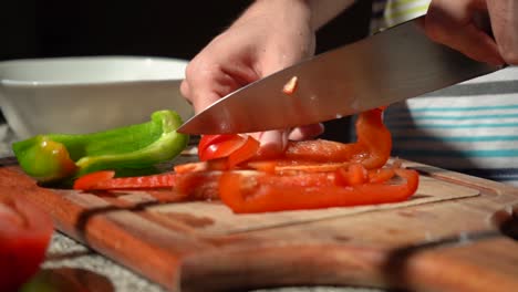 Person-Slicing-Red-Bell-Pepper-With-Knife-On-Chopping-Board-In-The-Kitchen
