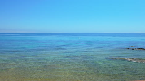 wooden stairs leading to the turquoise waters of the mediterranean sea in marbella, spain, under a clear blue sky