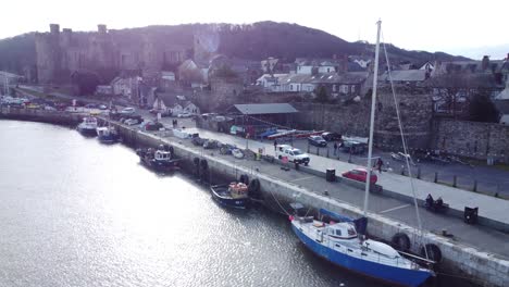 picturesque conwy castle and harbour fishing town boats on coastal waterfront aerial low angle dolly forward left