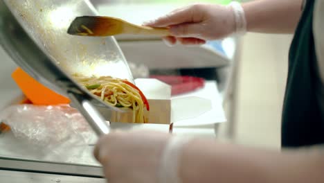 el cocinero coloca los fideos con verduras en el paquete.