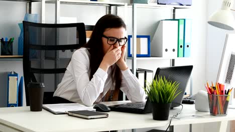mujer de negocios bostezando y usando una computadora portátil en una oficina moderna