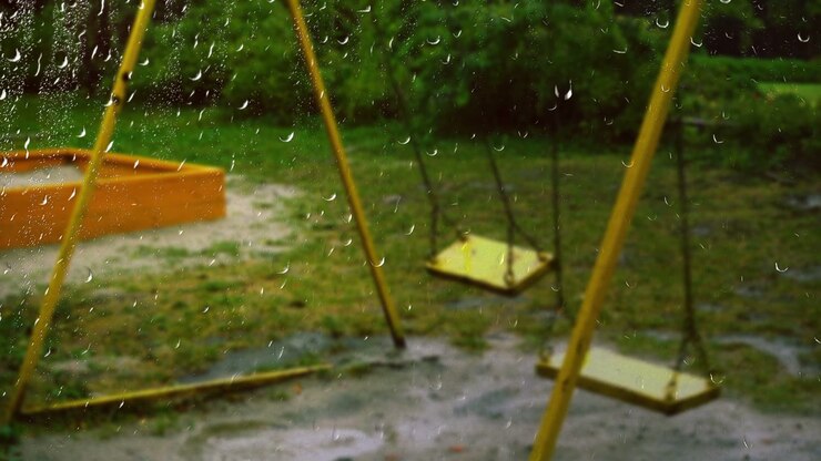 Swing during the rain. View from the window. Raindrops on the glass.