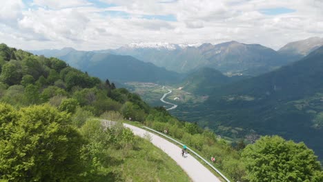 骑自行车的人在风景如画的山谷上方骑山路,滑翔<unk>飞过,空中