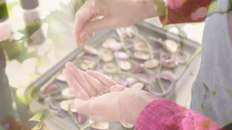 biracial woman seasoning chopped vegetables in kitchen, cooking over spots of light