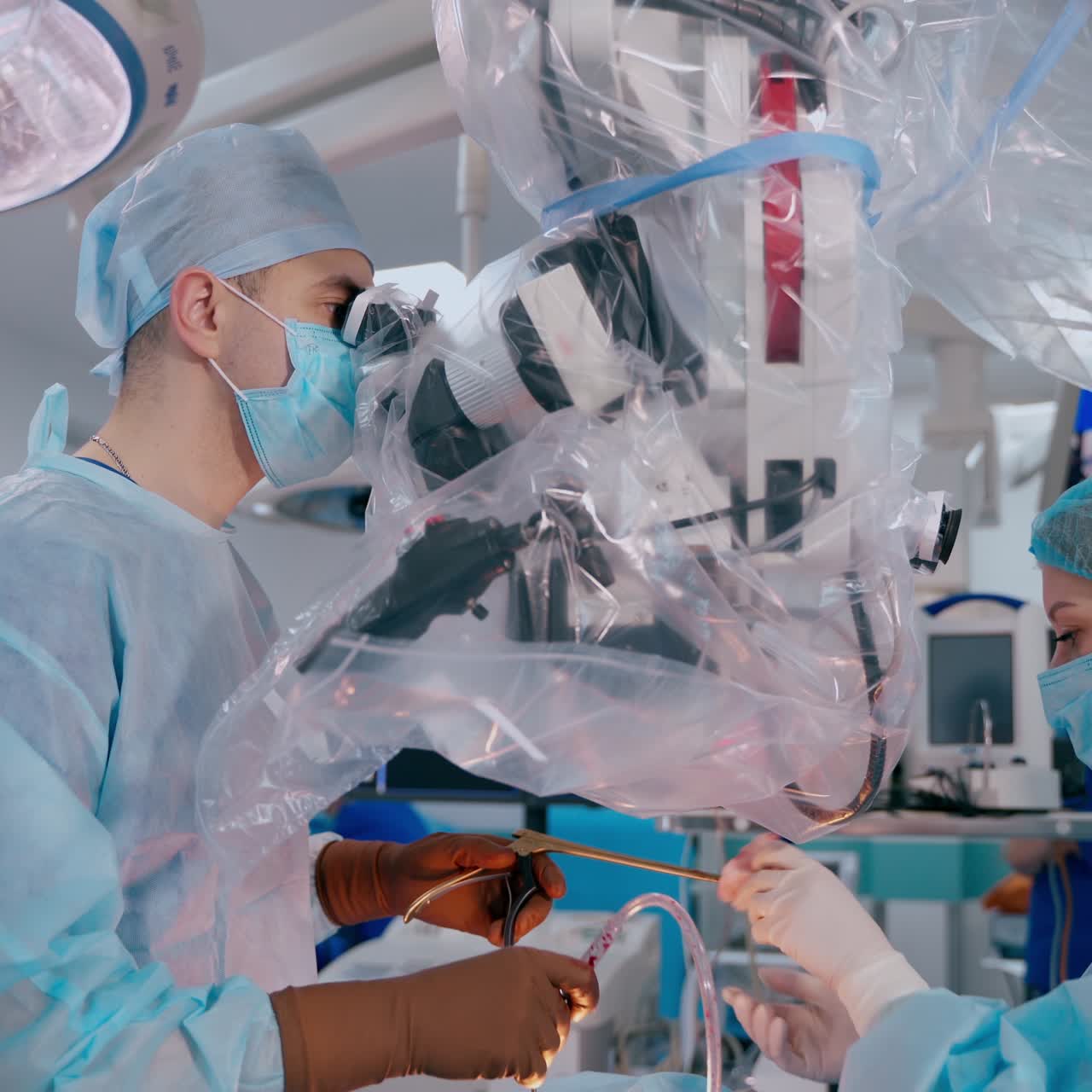 Neurosurgery through the microscope. Medical specialist looking into the microscope while doing an operation on a patient's body in the modern hospital.