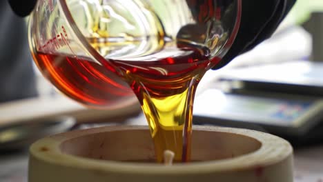 precise pouring technique demonstrated in candle-making process involving vibrant colored wax being transferred into candle molds