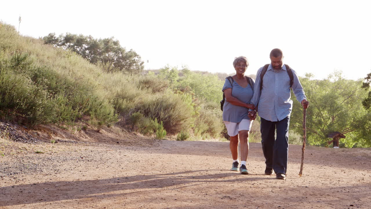 pareja de ancianos con mochilas caminando juntos en el campo