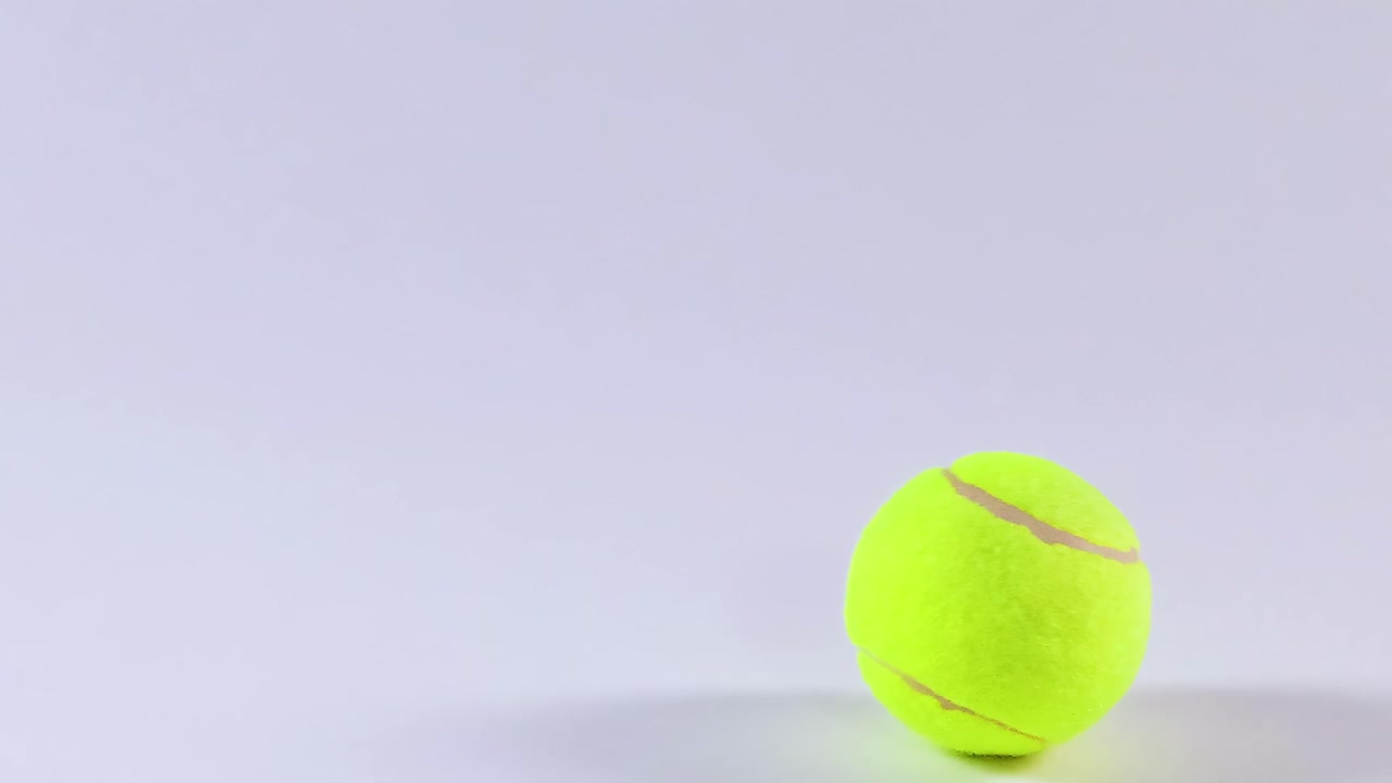 A tennis ball moves across a plain white background, showcasing its vibrant color and simple motion.
