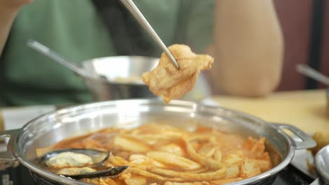 젓가락으로 한국 김치국에서 떡볶이를 사용하면서 클로즈업
