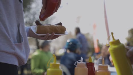 a slow motion shot of a man pouring ketchup over a hot dog