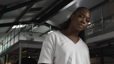 head and shoulders portrait of young woman inside office building or warehouse looking at camera