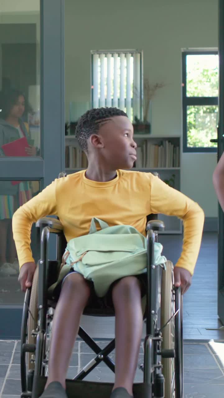 Vertical video: Rolling kid in wheelchair in yellow top crossing home door, backpacks urging exit