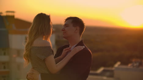 Young-couple-in-love-standing-on-the-roof-hug-and-closely-look-at-each-other.-Romantic-evening-on-the-roof-of-the-building.-A-date-on-the-roof-of-a-building-love.-Slow-motion