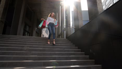 cheerful girl walking from centre mall with shopping bags, happy with purchase on black friday