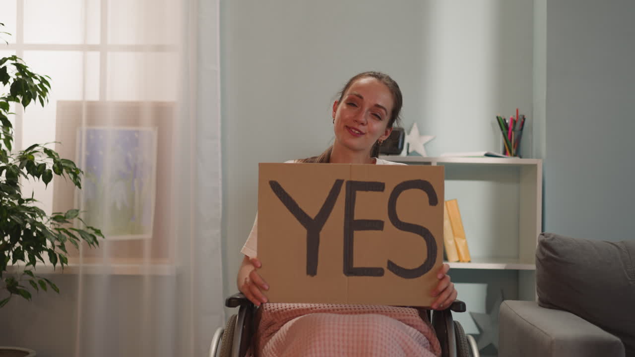 긍정적 인 장애인 여성 은 "예"라는 단어 가 새겨진 포스터 를 들고 미소 짓는다