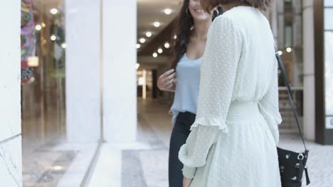 unrecognizable women standing near shop-window