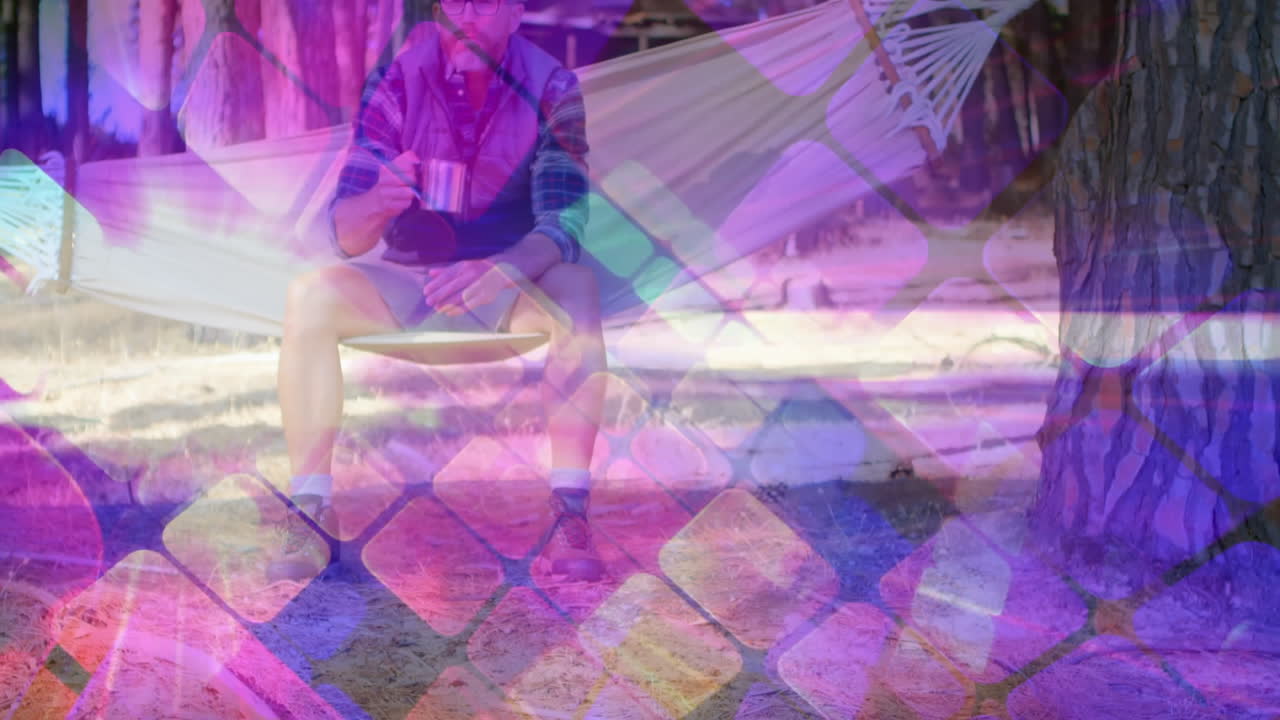 male hiker sitting in hammock forest camp, holding mug and displaying animated health data graphs