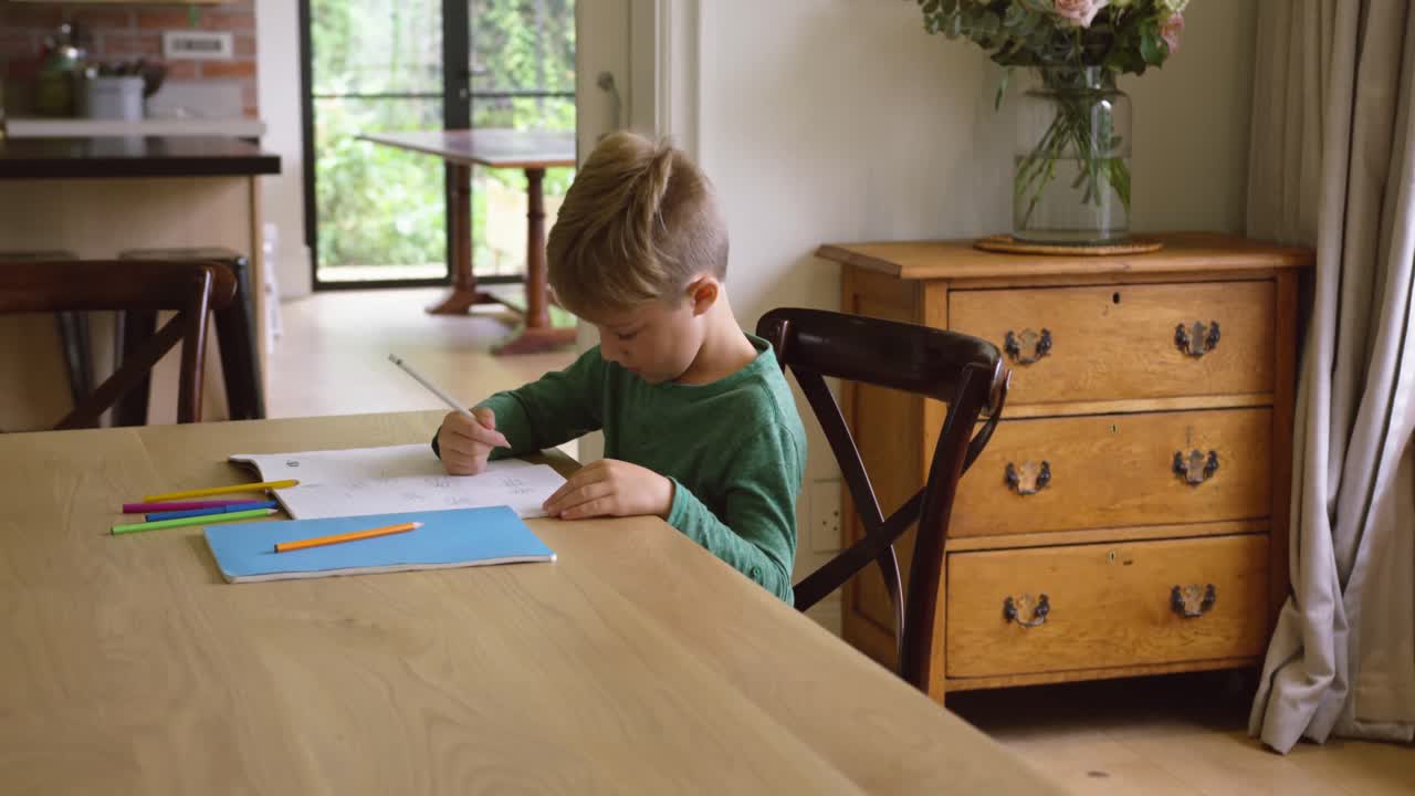 Cute boy doing homework at dining table in a comfortable home 4k