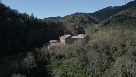warm sunlight illuminating unused font picant spa nestled in verdant wooded valley of sant hilari sacalm, revealing architectural heritage within serene catalonian landscape