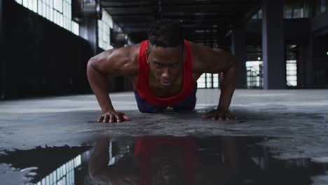 hombre afroamericano haciendo flexiones en un edificio urbano vacío