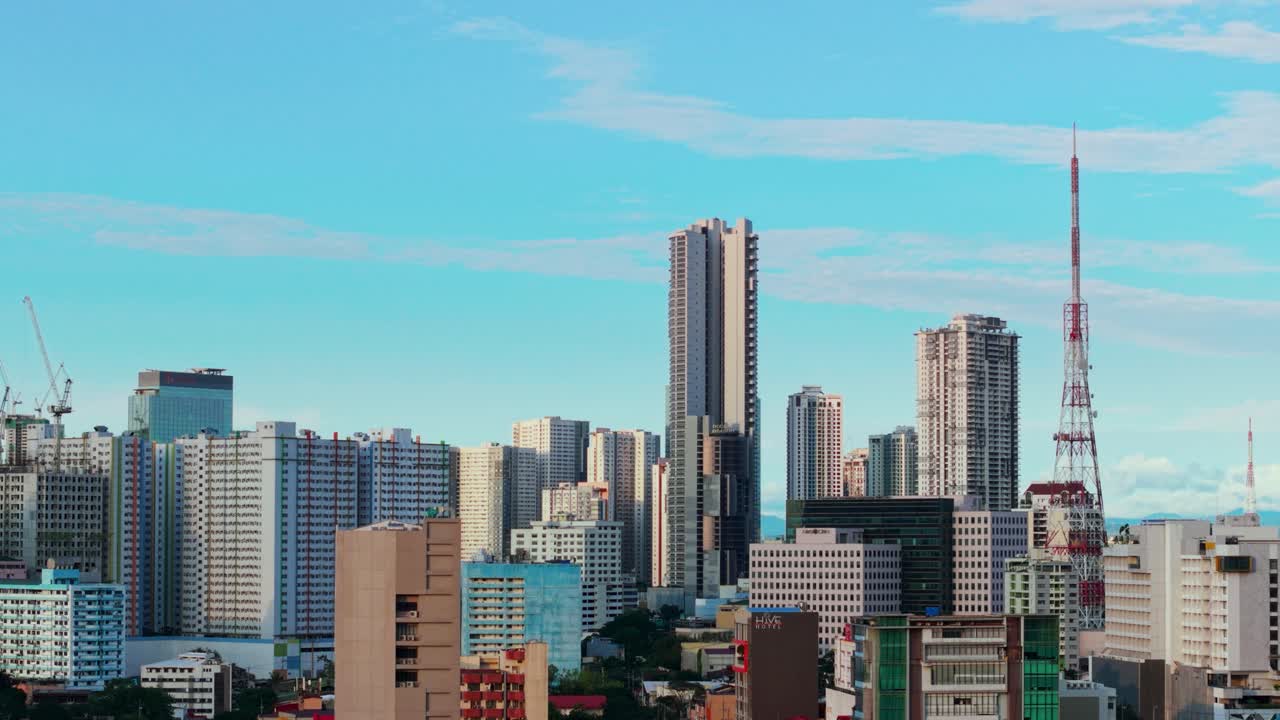 A stunning aerial shot of Quezon City, Philippines, showcasing the vibrant cityscape under a clear blue sky. The scene features a mix of towering skyscrapers and mid-rise buildings.