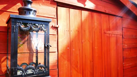 decorative black metal lantern hanging outside red wooden english garden shed