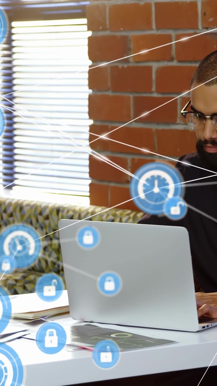 Video verticale: Uomo che digita su un laptop in un ambiente tecnologico, con icona HUD blu scintillante e collegamenti di blocco che proteggono il laptop.