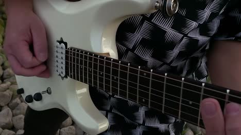 a guitarist plays on the rocky shore